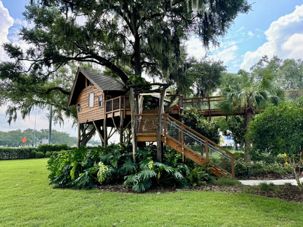 A custom treehouse at Wish Farms in Florida, featuring an elegant arched roofline, natural wood finishes, and expansive windows that offer breathtaking views of the surrounding farm and lush landscape.